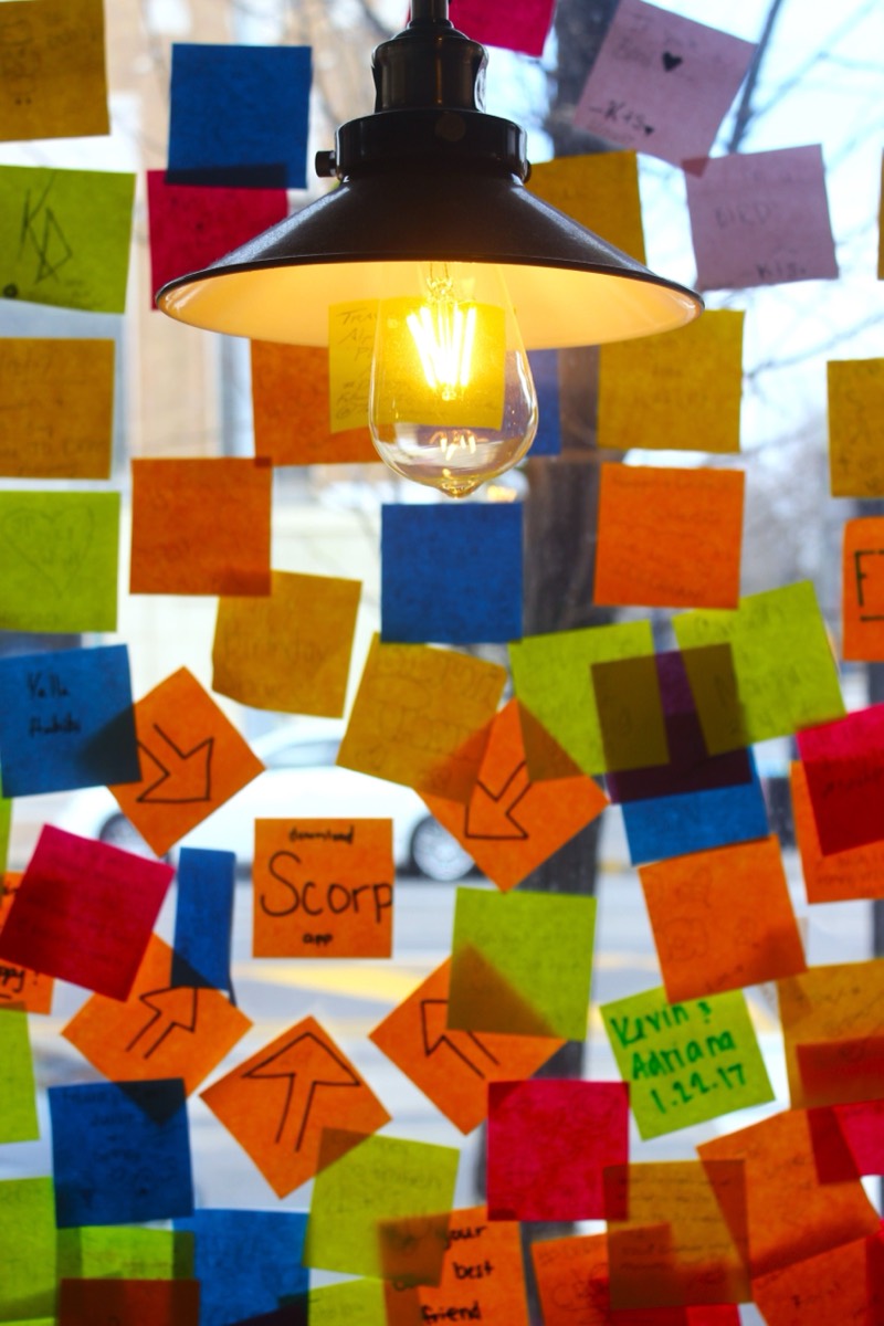 Una lampadina accesa davanti a una vetrina coperta di foglietti adesivi colorati